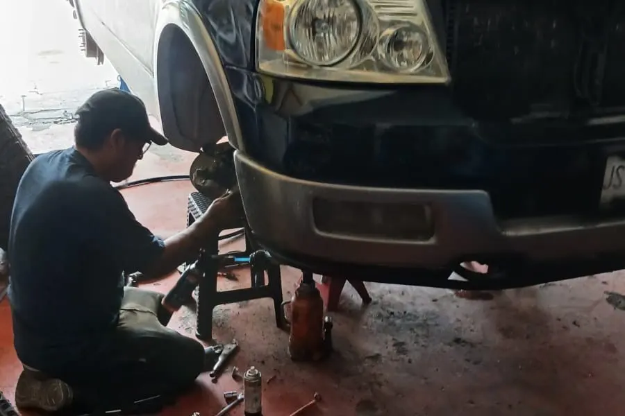 Mecánico de Tajuza trabajando en la suspensión delantera de una camioneta Ford F-150